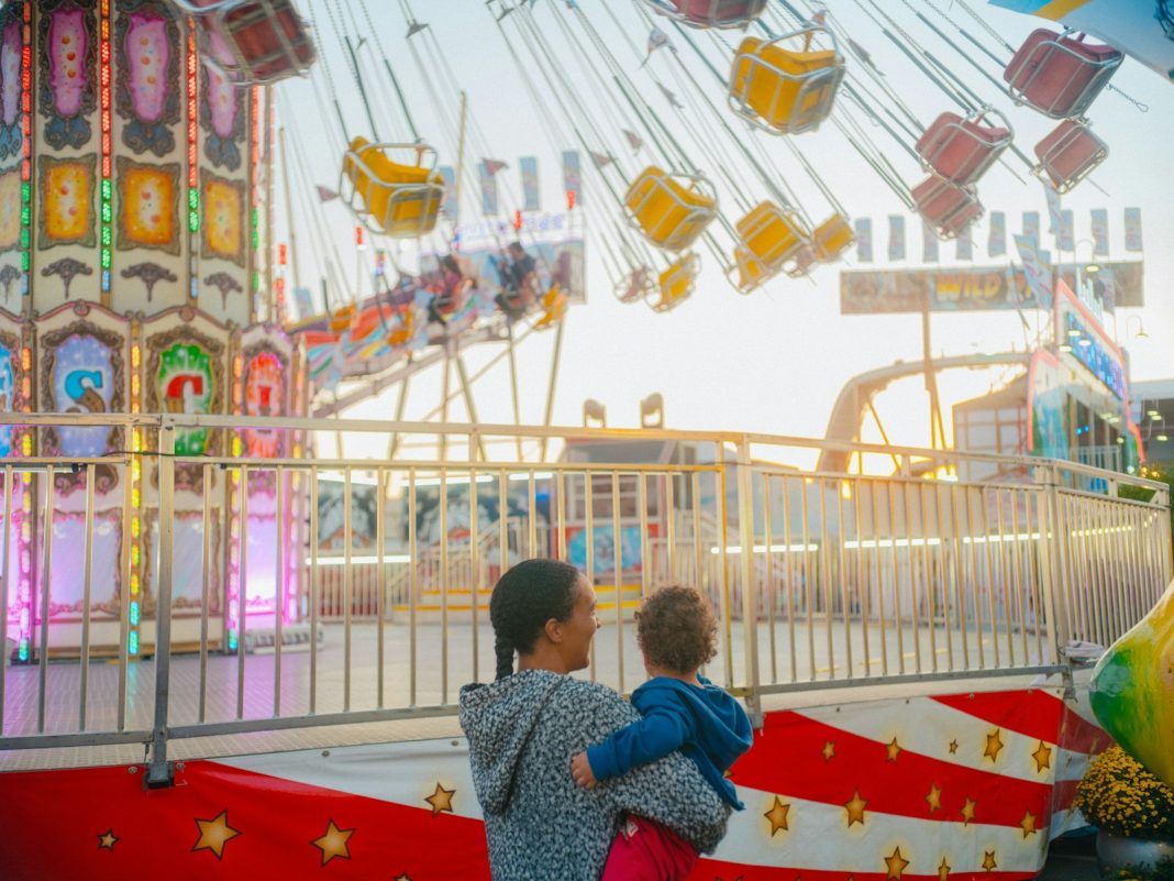 Two children standing in front of a carnival ride