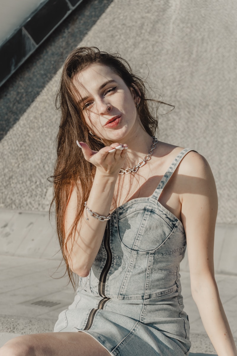 Woman in denim dress blowing a kiss