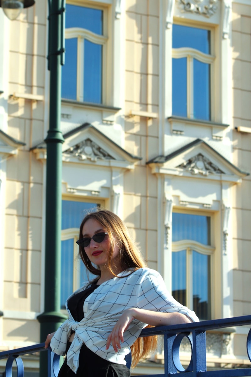 A woman is standing on a railing in front of a building
