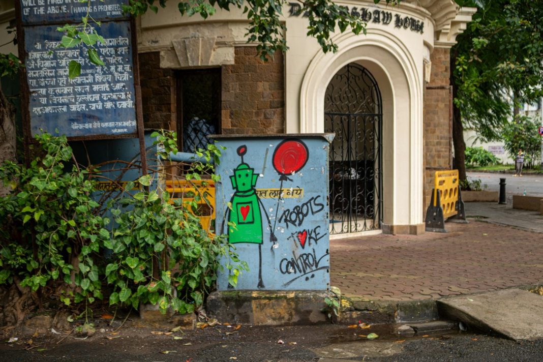 Street art depicts a green robot holding a balloon.